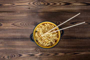 instant noodles in wooden bowl,and chopsticks on plate