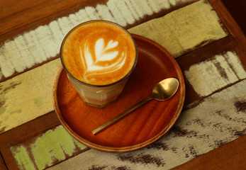 Hot art latte coffee in a cup on old wooden table.