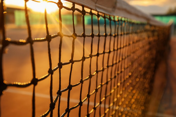 Tennis net on court at sunset - obrazy, fototapety, plakaty