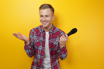Young presenter with microphone on color background - obrazy, fototapety, plakaty