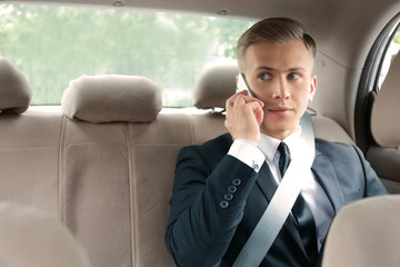 Young businessman talking on phone in car