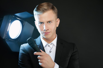 Young presenter with microphone on black background