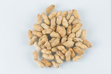 Roasted in shell peanuts scattered on a white background