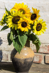 Sunflowers in vintage clay jug on wooden table