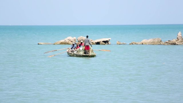 Long shot of a small boat filled with men on ocean waters near Port-au-Prince