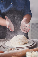 Woman baker knead and sprinkle yeast dough with eggs and flour