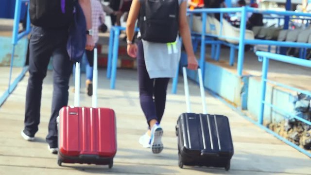 Attractive happy couple with a backpack and carrying luggage arriving the pier, view from the back, slow motion. 1920x1080, hd, Vacation concept, blurred background