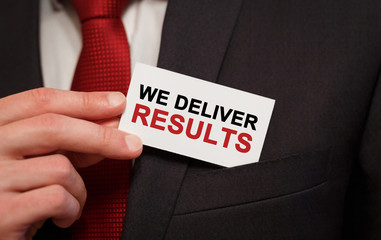 Businessman putting a card with text We Deliver Results in the pocket