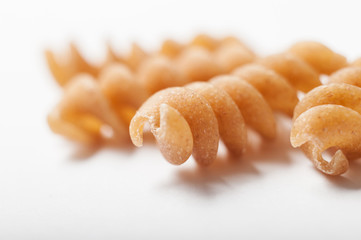 Whole wheat rotini pasta shapes on a white background