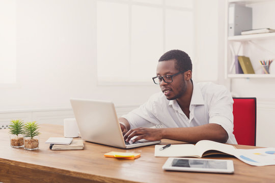 Black businessman in white office, work with laptop