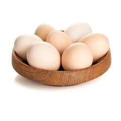 chicken eggs in a wooden plate isolated on white background