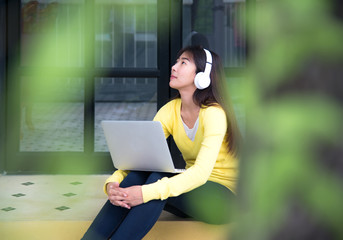Fototapeta premium Lifestyle Girl enjoy listening music and play laptop in the nature park. Music and Lifestyle Concept.