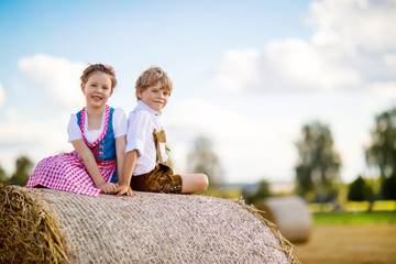 Two kids, boy and girl in traditional Bavarian costumes in wheat field