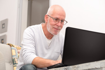 Senior man with laptop sitting in sofa