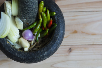 Preparation of cooking ingredients using Pestle and grey granite mortar, on wooden table, selective focus