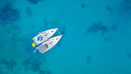 Obraz premium Aerial view of two sailing boats anchoring next to reef