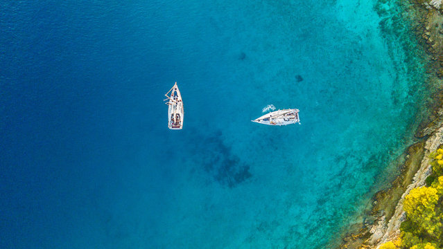 Aerial view of two sailing boats anchoring next to reef