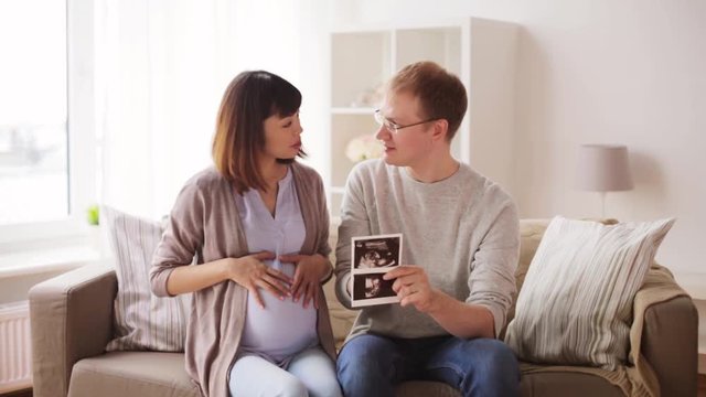 happy couple with ultrasound images at home