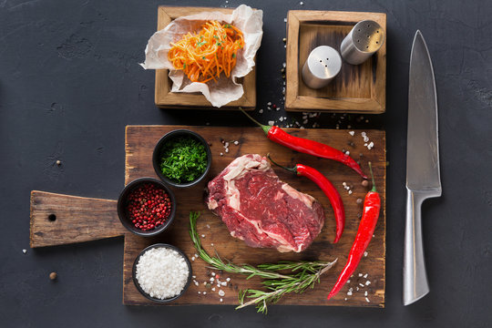 Rib eye steak with spices on wooden desk with russian korean salad