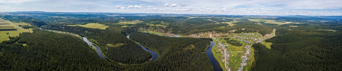 Fototapeta na wymiar panorama of area a village hidden among the mountains and forests. Aerial view