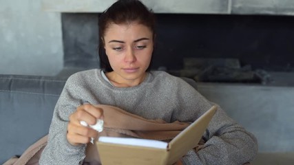 Exhausted young woman blowing red nose with tissue