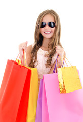 Adorable little girl child in sunglasses holding shopping colorful paper bags