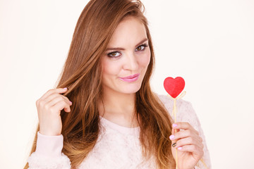 Flirty woman holding red wooden heart on stick