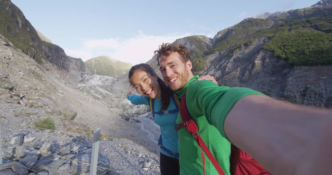 Happy lifestyle couple selfie video. New Zealand tourists smiling happy in nature by Franz Josef Glacier, Westland Tai Poutini National Park, South Island, New Zealand. Couple having fun on travel.