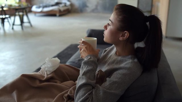 Sick young woman warming up with tea