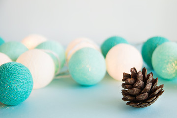 Cone on the blue background with blue and white lights made of yarn threads, closeup. Christmas decorations.