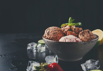 Portion of ice cream scoops with fruit on black