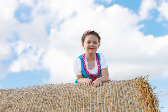 Cute little kid girl in traditional Bavarian costume in wheat field