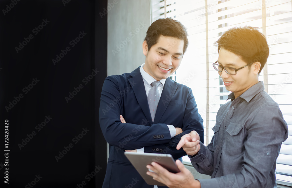 Poster Two Asian handsome businessmen using touchpad with partners discussing documents and ideas at meeting and  smiling happy for working