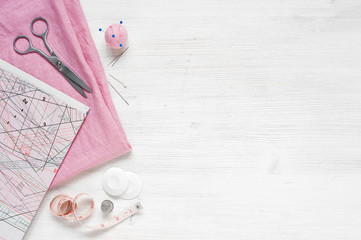 Pink natural fabric and sewing tools on  the white wooden table - obrazy, fototapety, plakaty
