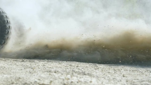 Wheel of ATV starting to spin and kicking up ground or dirt. Quad begin the movement. Slow motion Close up