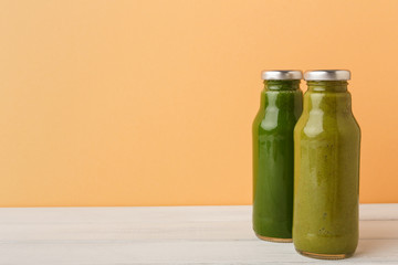 Assortment of detox smoothies in glass bottles on wall background.