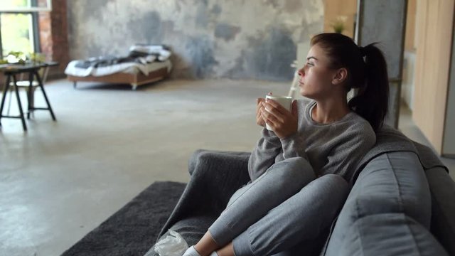Tired ill woman warming up and drinking tea