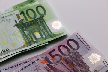 Two piles of euro banknotes on a white background