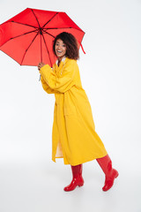 Full length image of Smiling african woman in raincoat