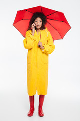 Full length image of surprised african woman in raincoat