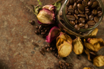 top view of coffee beans inside a jar, sorrounded by dried rose