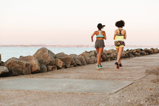Full length back view image of two fitness women running