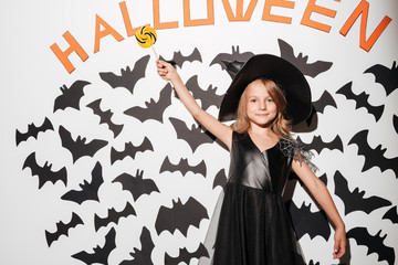 Cute little girl dressed in halloween costume holding lollipop
