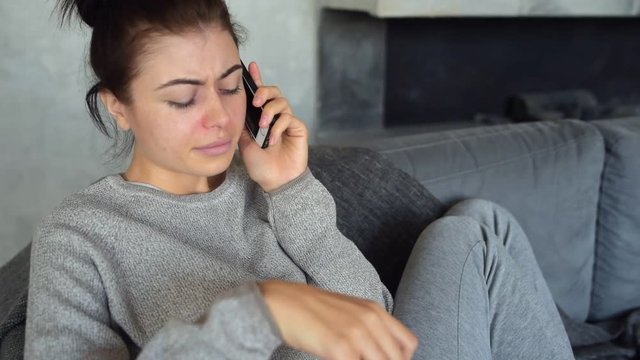 Frustrated ill lady talking on phone at home