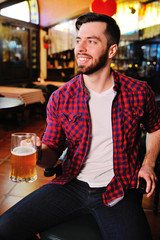 A pub visitor drinks beer from a large beer glass while sitting on a chair