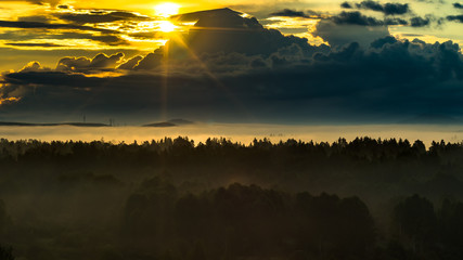 New life concept: gorgeous an promising scene of dark mountain range and foggy valley in the first rays of the sun beaming through clouds in the summer morning, golden hour © Eugene Put