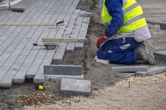Worker installing paver sidewalk