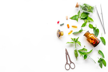 Herbal medicine. Leaves, bottles, pills and sciccors on white background top view copyspace