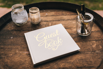 Guest book on wooden barrel surrounded by glasses - obrazy, fototapety, plakaty