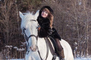 Fototapeta premium Nice girl and white horse in a forest in a winter